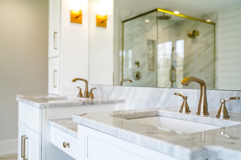 Bright bathroom with stone vanities and brass taps