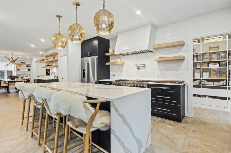 Stone waterfall island in a bright kitchen